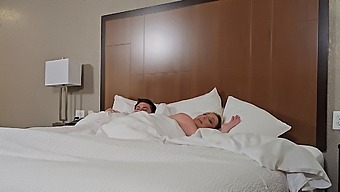 A Blonde Stepmom And Her Stepson Cuddle In Bed In A Hotel